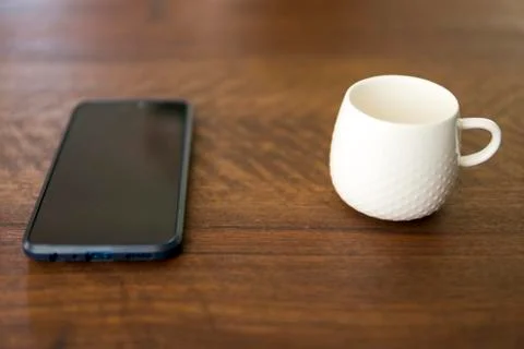 Empty white cup next to smartphone Stock Photos