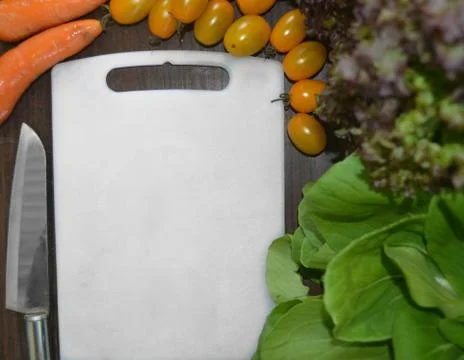 Empty white cutting board in the middle of vegetables and knife Stock Photos