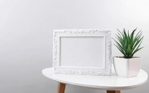 Empty white decorative frame on a table with plant Stock Photos