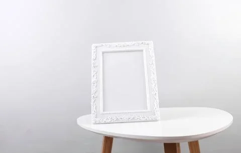 Empty white decorative picture frame on a small table Stock Photos