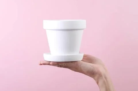 Empty white flower pot held in hand against pink background Foto stock