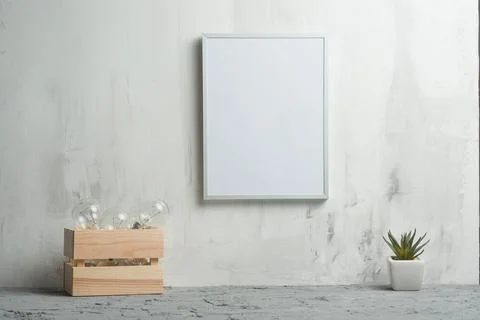 Empty white frame with a flower and bulbs on the wall background. The concept Stock Photos
