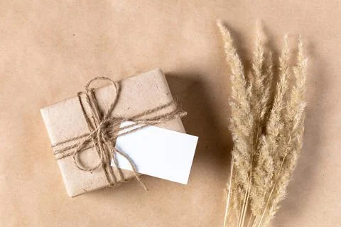 Empty white gift tag mock up on craft paper box with dried spikelets decorati Stock-Fotos
