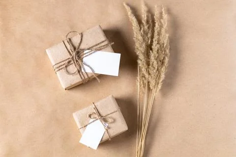 Empty white gift tag mock up on craft paper box with dried spikelets decorati Stock Photos