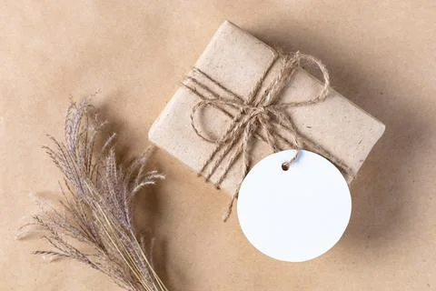Empty white gift tag mock up on craft paper box with dried spikelets decorati Stock Photos
