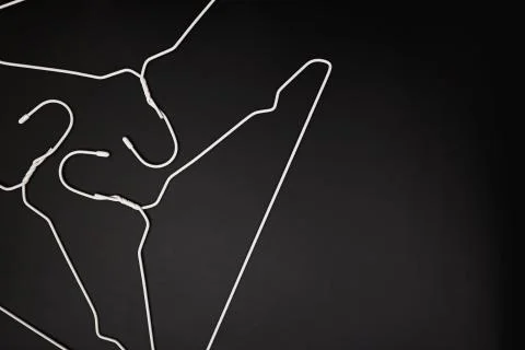 Empty white hangers lying on black background Stock Photos