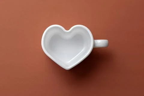 Empty white heart-shaped cup on a red background.Top view Stock Photos