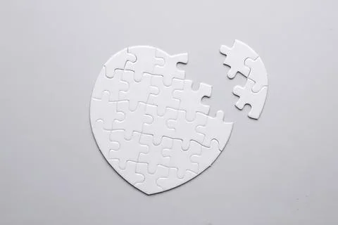 Empty white jigsaw puzzle in the shape of a heart with one piece missing Stock Photos