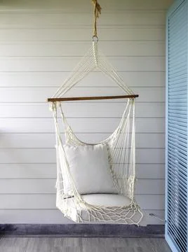 Empty white knitting rope swing hanging from ceiling on white wood background Stock Photos