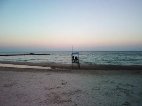 Empty white lifeguard tower with two people on the beach in windy weather.Sunset Stock-Fotos