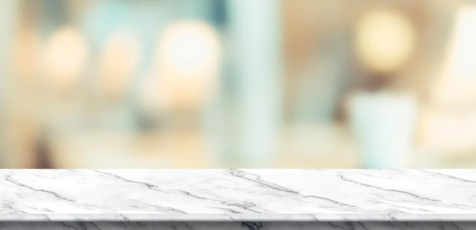 Empty white marble table and blurred soft light table in luxury restaurant wi Stock Photos
