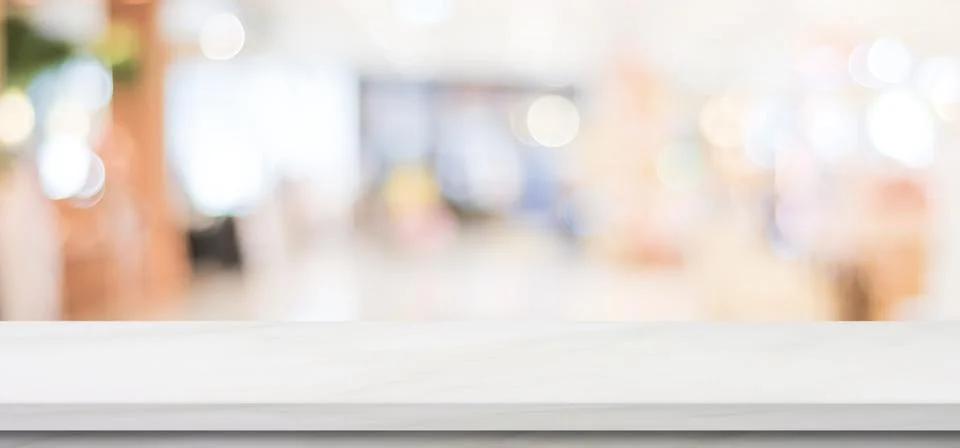 Empty white marble table over blur store background, banner, product display Stock Photos