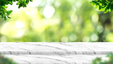 Empty white marble table top with blur tree in park with bokeh light at backg Stock Photos