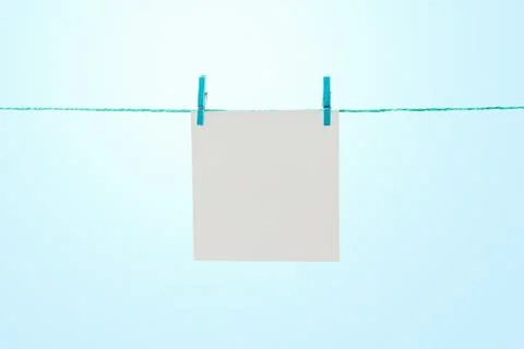 Empty white note paper hanging on rope against sunny blue sky with copy space Foto stock