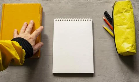 An empty white notebook, a book, and a yellow pencil case. Top view of object Stock Photos