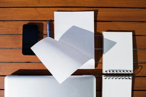 Empty white notepad with blue ballpoint pen and mobile phone and laptop Stock Photos