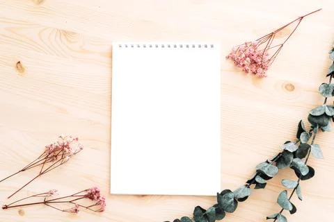 Empty white notepad with dried flowers on wooden table Stock Photos