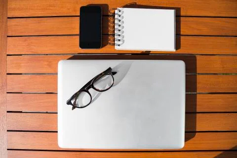 Empty white notepad with mobile phone, laptop and sight glasses Stock Photos