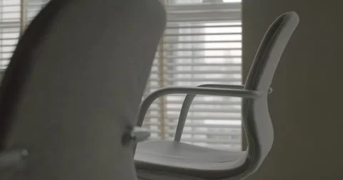 Empty white office chair slowly rotating in a room with a window Stock Footage 345543913