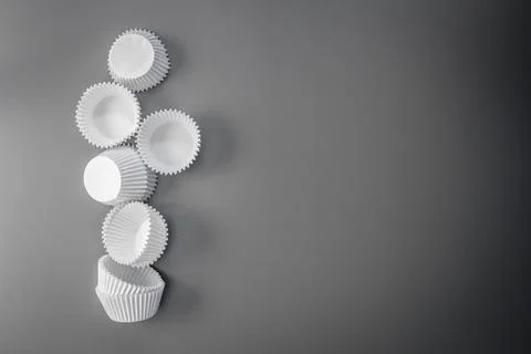 Empty white paper baking for muffins and cupcakes on gray background. Stock Photos