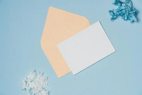Empty white paper list with envelope and flowers on blue background from ab.. Stock Photos