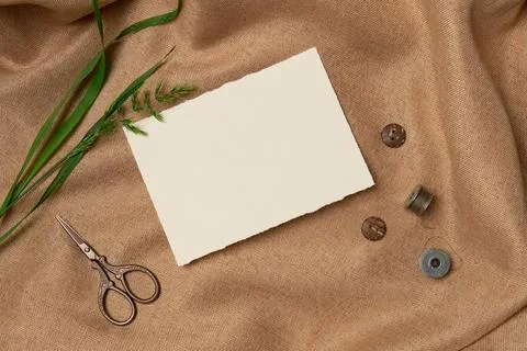 Empty white paper list with scissors and buttons on a fabric background from  Stock Photos