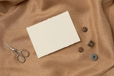 Empty white paper list with scissors and buttons on a fabric background fro.. Stock Photos