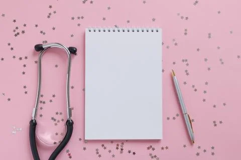 Empty white paper sheet notebook, pen, phonendoscope on a pink background Stock Photos