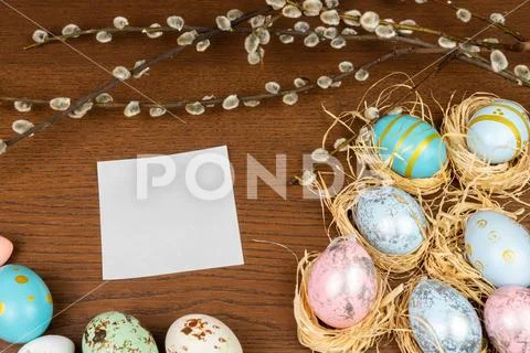 Empty white paper on a wooden table framed with easter eggs and willow twigs Stock Photos