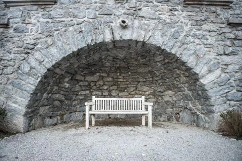 Empty white park bench under stone bridge Stock Photos