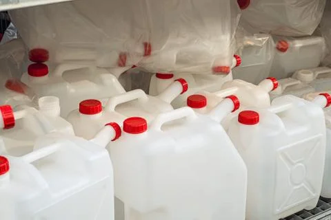 Empty white plastic cans with red lids on a rack Stock Photos