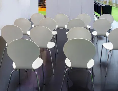 Empty white plastic chairs arranged for trade meeting inside room interior back Stock Photos