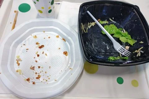 Empty white plastic plate and black bowl with fork after eating. Dirty dispos Stock Photos