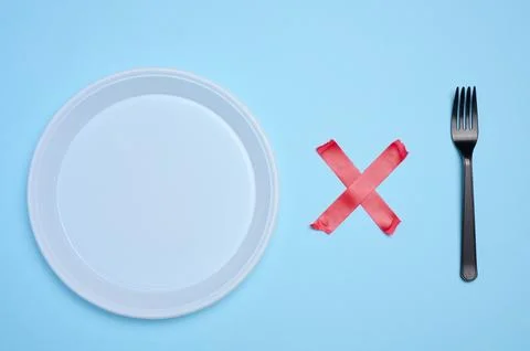 Empty white plastic plate and plastic fork is attached with red adhesive ta.. Stock Photos