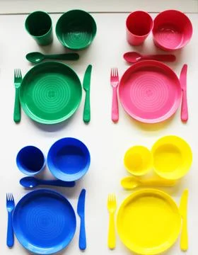 Empty white plastic plate, cup, fork and spoon over white background with copy Stock Photos
