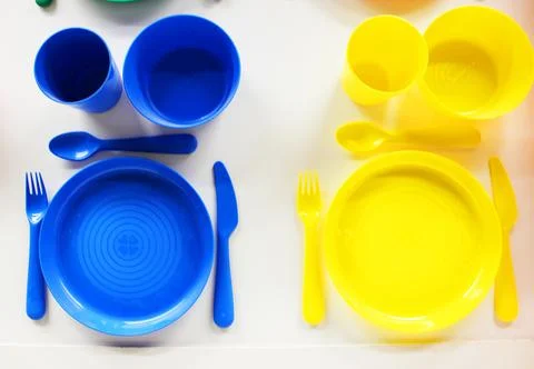 Empty white plastic plate, cup, fork and spoon over white background with copy Stock Photos