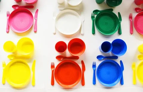 Empty white plastic plate, cup, fork and spoon over white background with copy Stock Photos