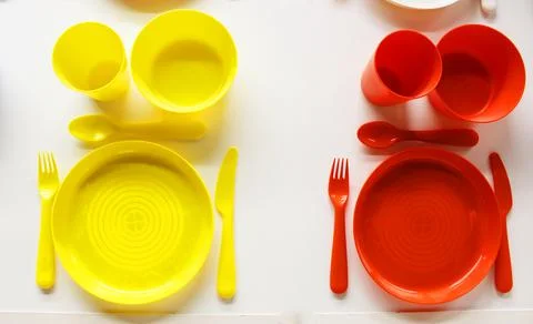 Empty white plastic plate, cup, fork and spoon over white background with copy Stock Photos