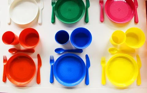 Empty white plastic plate, cup, fork and spoon over white background with copy Stock Photos