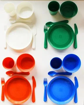 Empty white plastic plate, cup, fork and spoon over white background with copy Stock Photos