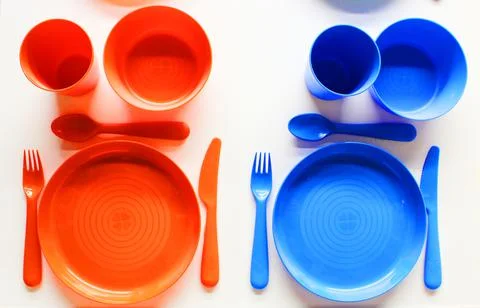 Empty white plastic plate, cup, fork and spoon over white background with copy Stock Photos