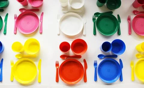 Empty white plastic plate, cup, fork and spoon over white background with copy Stock Photos