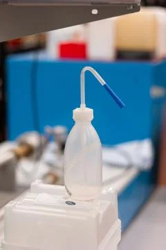 Empty white plastic squeeze bottle with tube nozzle in a lab shallow depth of Фото