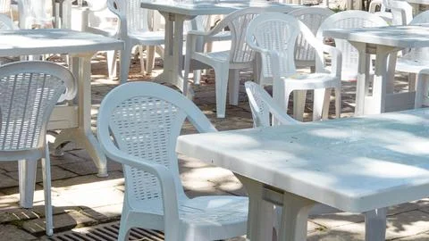 Empty white plastic tables and chairs on an outdoor cafe terrace. Stock Photos