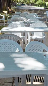 Empty white plastic tables and chairs in a park cafe. Stock Photos