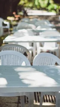 Empty white plastic tables and chairs in a park cafe. Stock Photos