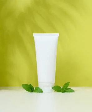 Empty white plastic tubes for cosmetics on a green background. Packaging f... Stock Photos