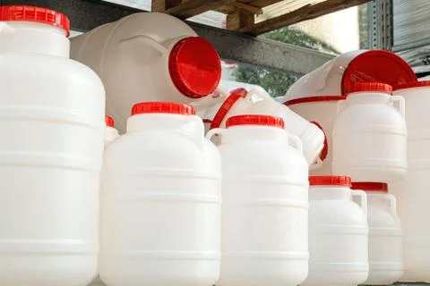 Empty white plastic water-cans with red lids on a rack Stock Photos