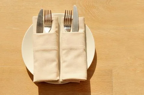 Empty white plate and silverware knife and fork on wooden background.  Stock Photos