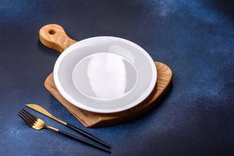 Empty white plate on blue background table. Flat lay Stock Photos